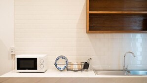 A kitchen with a microwave, a sink, and a dish rack.