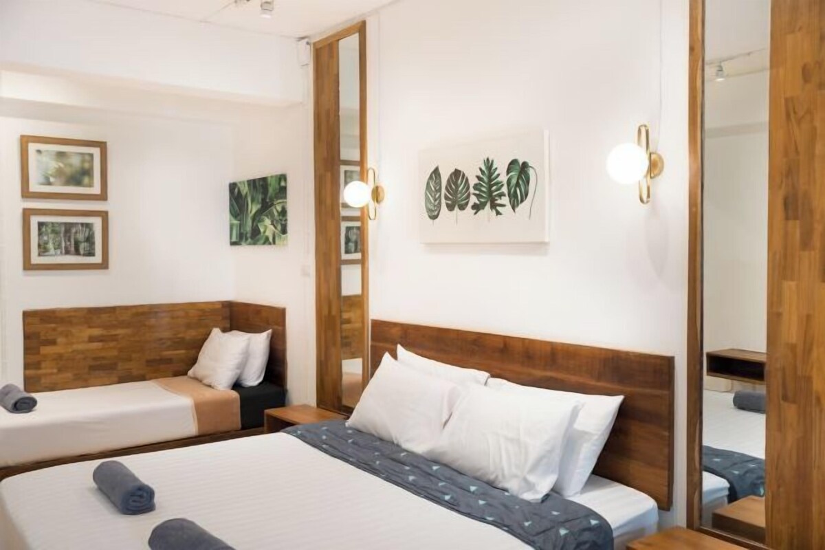 A hotel room with two beds, a wooden headboard, a large mirror, and wall art.
