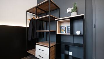 A modern, multi-tiered shelving unit with a wooden top, a white drawer, and a small shelf with a plant and a book.