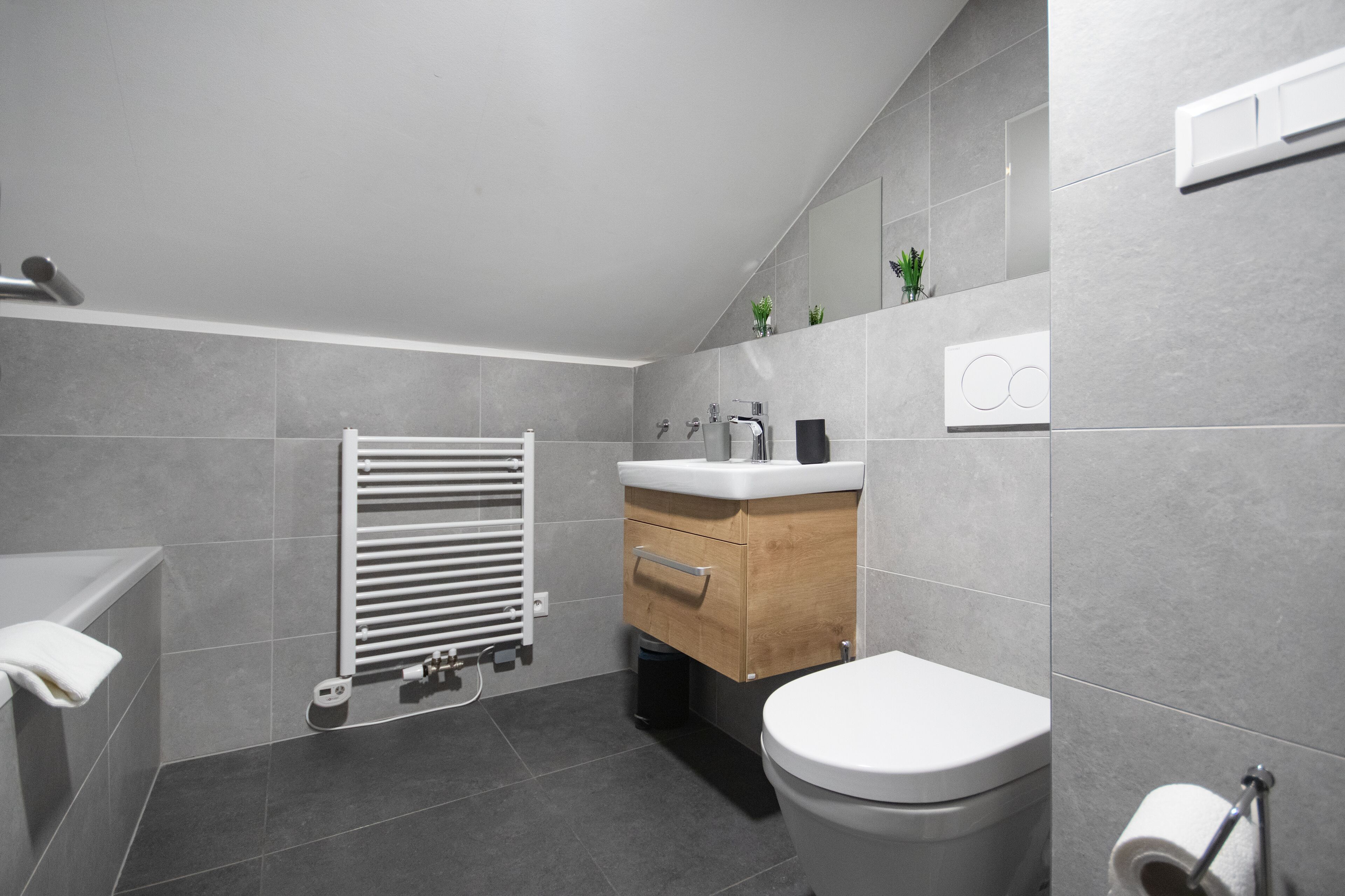 Une salle de bain moderne équipée de toilettes, d’un lavabo et d’un porte-serviettes.