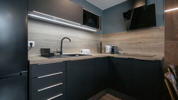 Una cocina moderna con armarios oscuros, un microondas, una cafetera y un bloque de cuchillos.