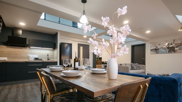 A modern dining area with a wooden table, chairs, and a vase of flowers. - CORU House (Prague)