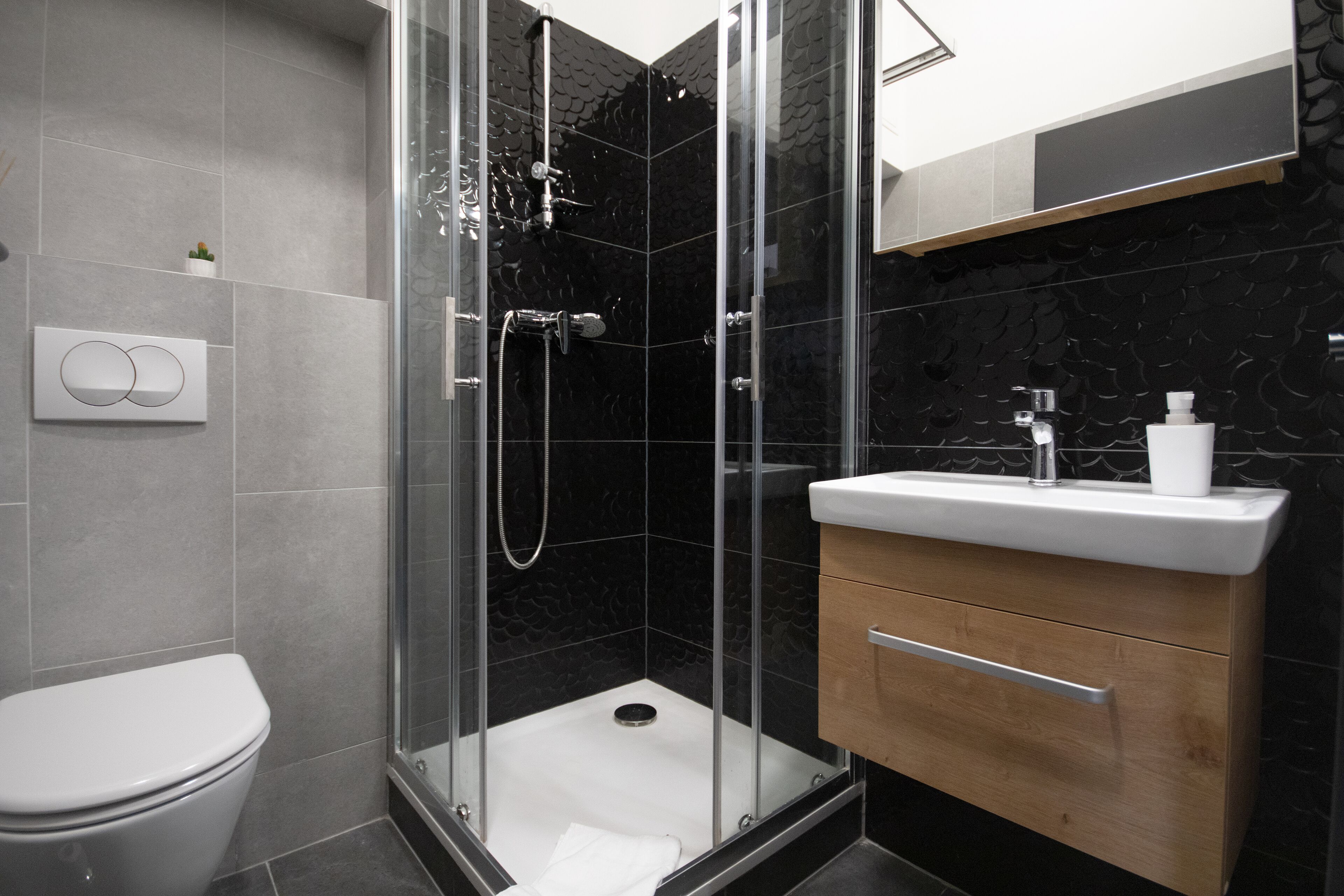 A modern bathroom with a glass-enclosed shower, a toilet, and a vanity with a sink and storage.