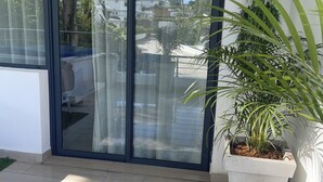 Ein moderner Balkon mit einer Schiebeglastür, Topfpflanzen und Blick auf ein Wohngebiet.