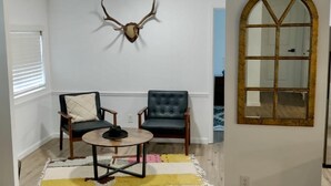 A room with two chairs, a round table, a mounted antler, and a large arched window. - Cozy Lake House Surrounded by Mountain's (Wofford Heights)