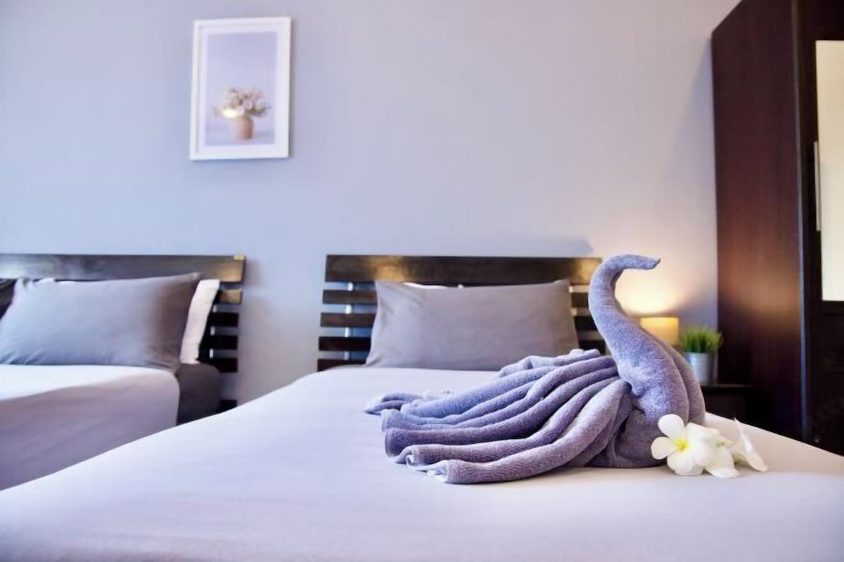 Une chambre d’hôtel avec deux lits, un tableau encadré au mur et une serviette décorative posée sur le lit.