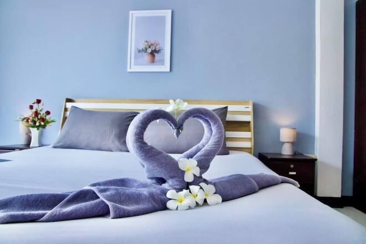 Ein Hotelzimmer mit Bett, Nachttisch, Lampe und einem gerahmten Bild an der Wand.