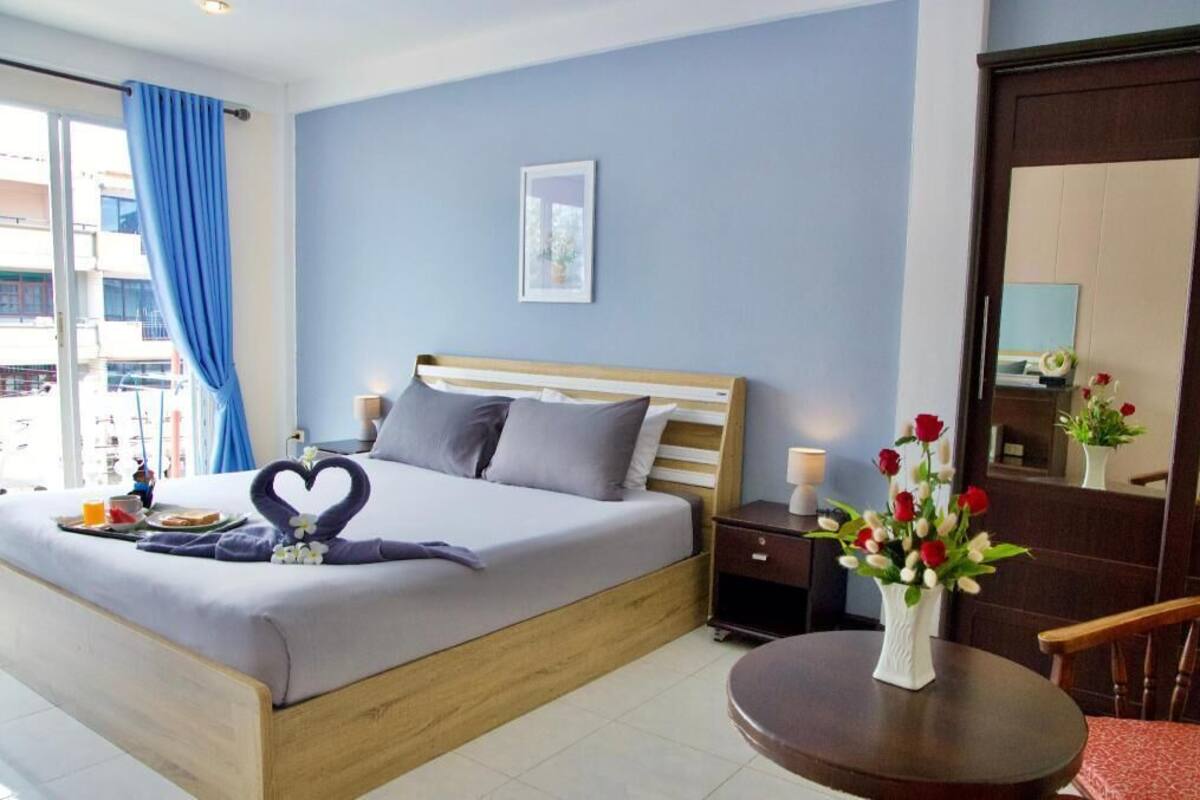 Ein Hotelzimmer mit einem Bett, einem Nachttisch und einem kleinen runden Tisch mit Blumen in einer Vase.