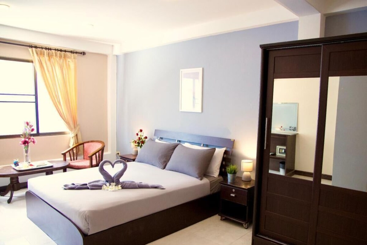 Una habitación de hotel con cama, mesita de noche, silla y armario.
