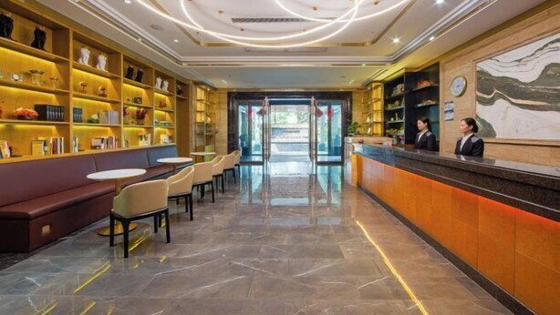 Un hall d’hôtel comprenant un comptoir d’accueil, un espace salon et des étagères ornées d’objets décoratifs.