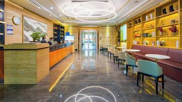 Un hall de hotel con mostrador de recepción, zona de estar y estanterías decorativas.
