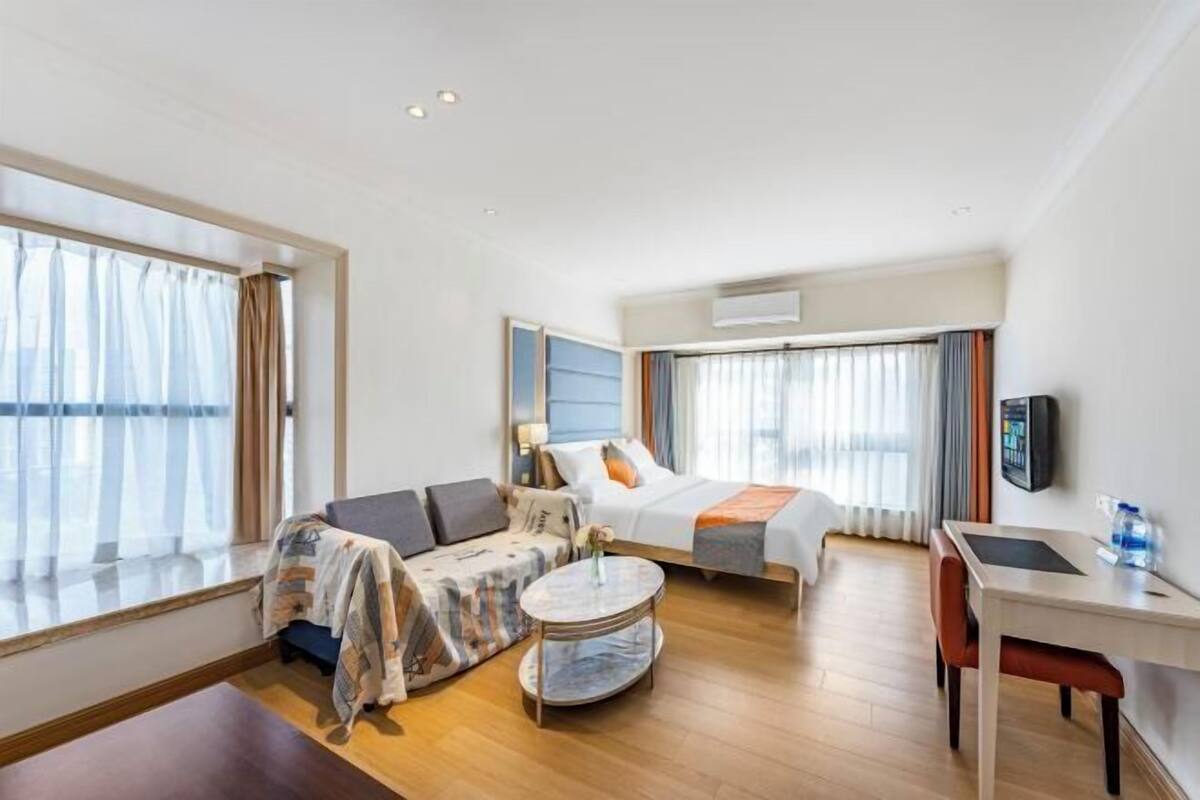 A hotel room with a bed, a sofa, a small table, and a desk.