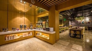 Un intérieur moderne avec un comptoir d’accueil en bois, un espace bar et un coin salon.