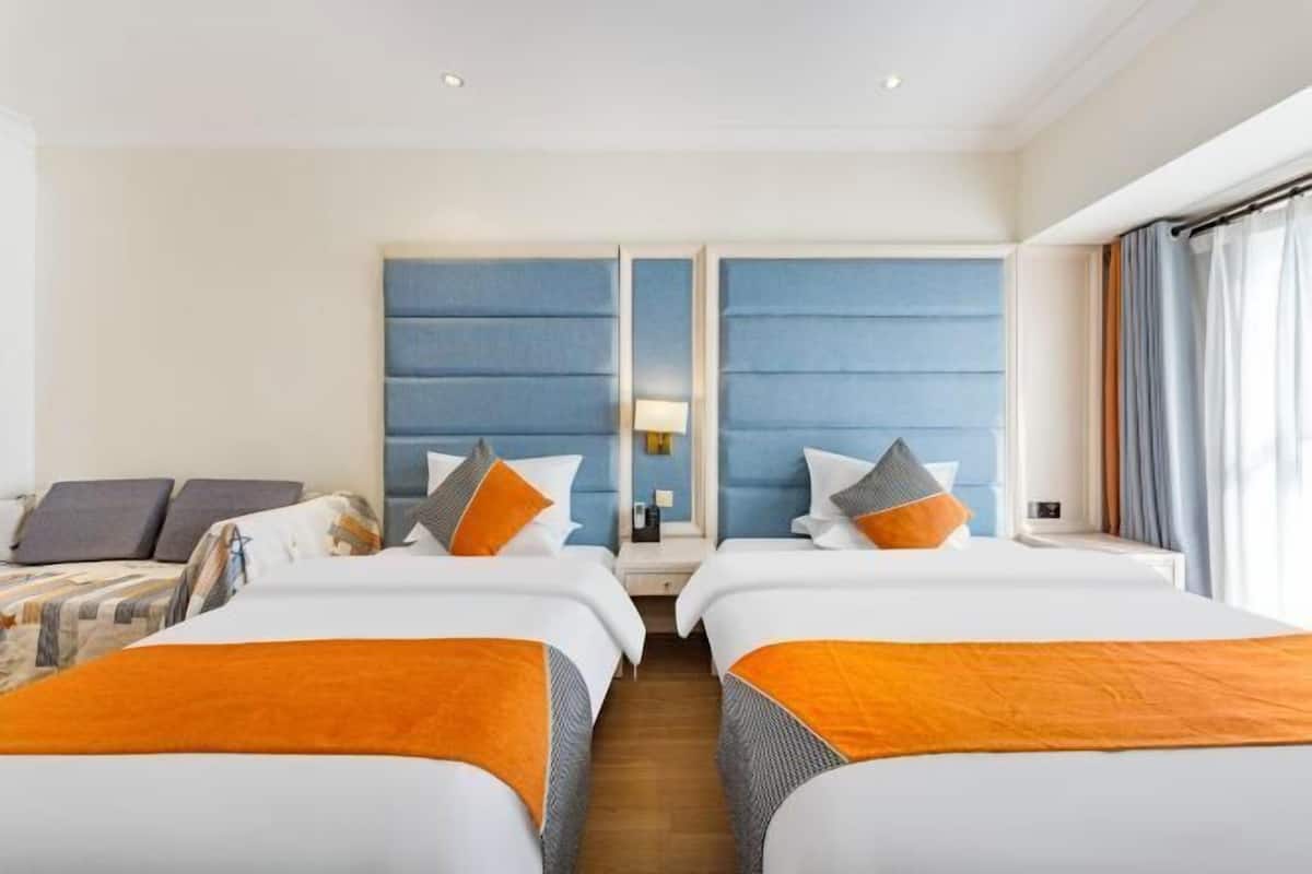 A hotel room with two beds, a large mirror, a nightstand, and a window with curtains.
