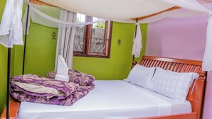 Una cama con dosel, una ventana con rejas y una pared verde.
