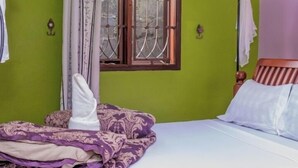 Una cama con dosel, paredes verdes, una ventana con barrotes y dos luces fijadas a la pared.