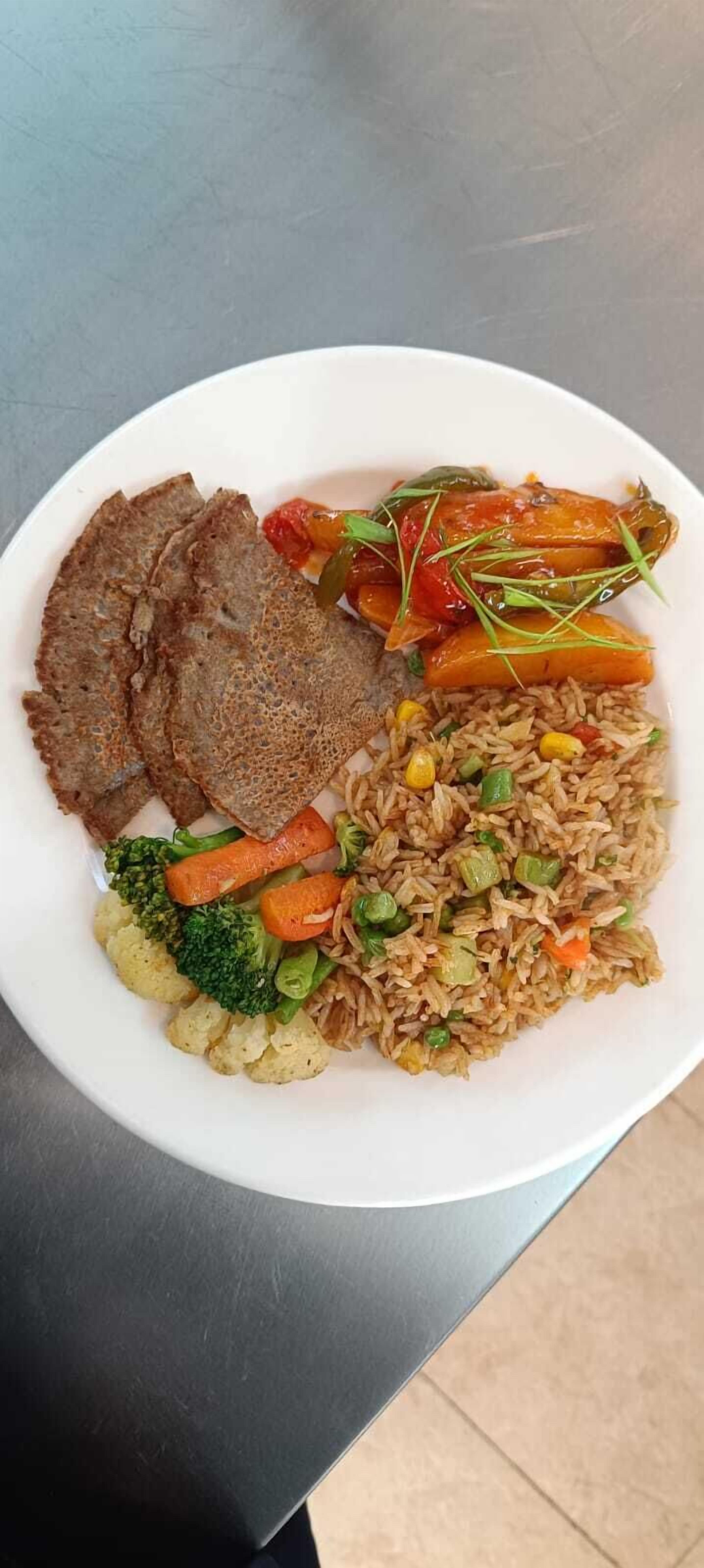 Un plato de comida con arroz, verduras y pan plano.