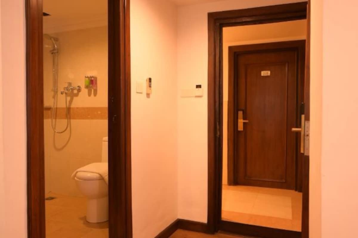 A hotel bathroom with a shower, toilet, and a wooden door.