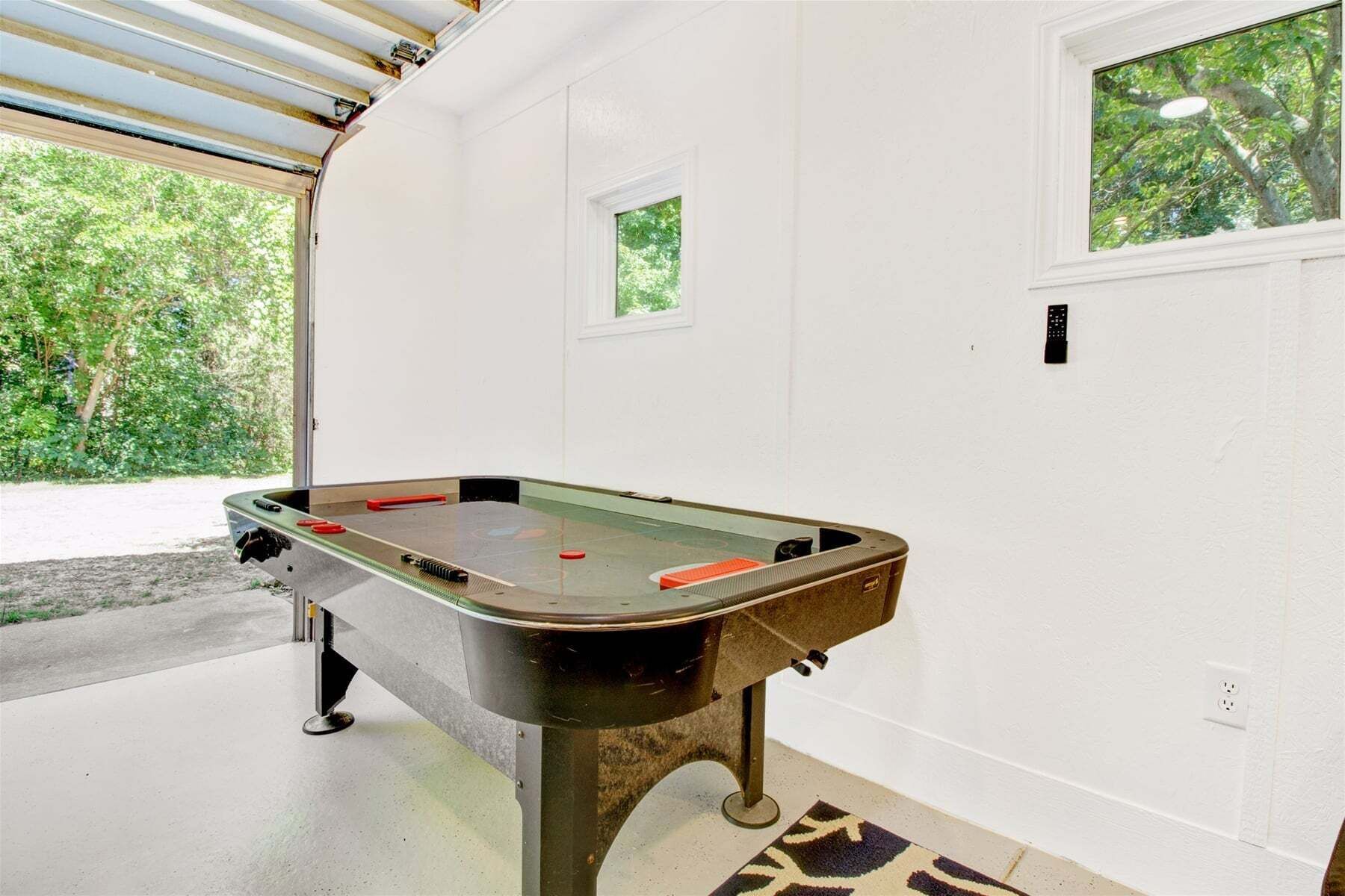 A pool table in a room with white walls, a small window, and a door.