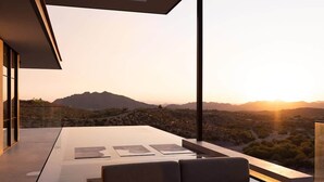 Un área de descanso moderna al aire libre con vistas a un paisaje desértico y montañas al atardecer.