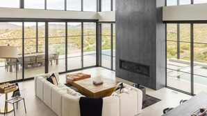 Una sala de estar moderna con chimenea, ventanas amplias y vistas al paisaje desértico.