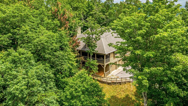 A secluded cabin surrounded by dense forest, with a covered porch and a stone pathway leading to the entrance.