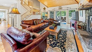 A spacious living room with a leather sofa, a coffee table, and a stone fireplace.