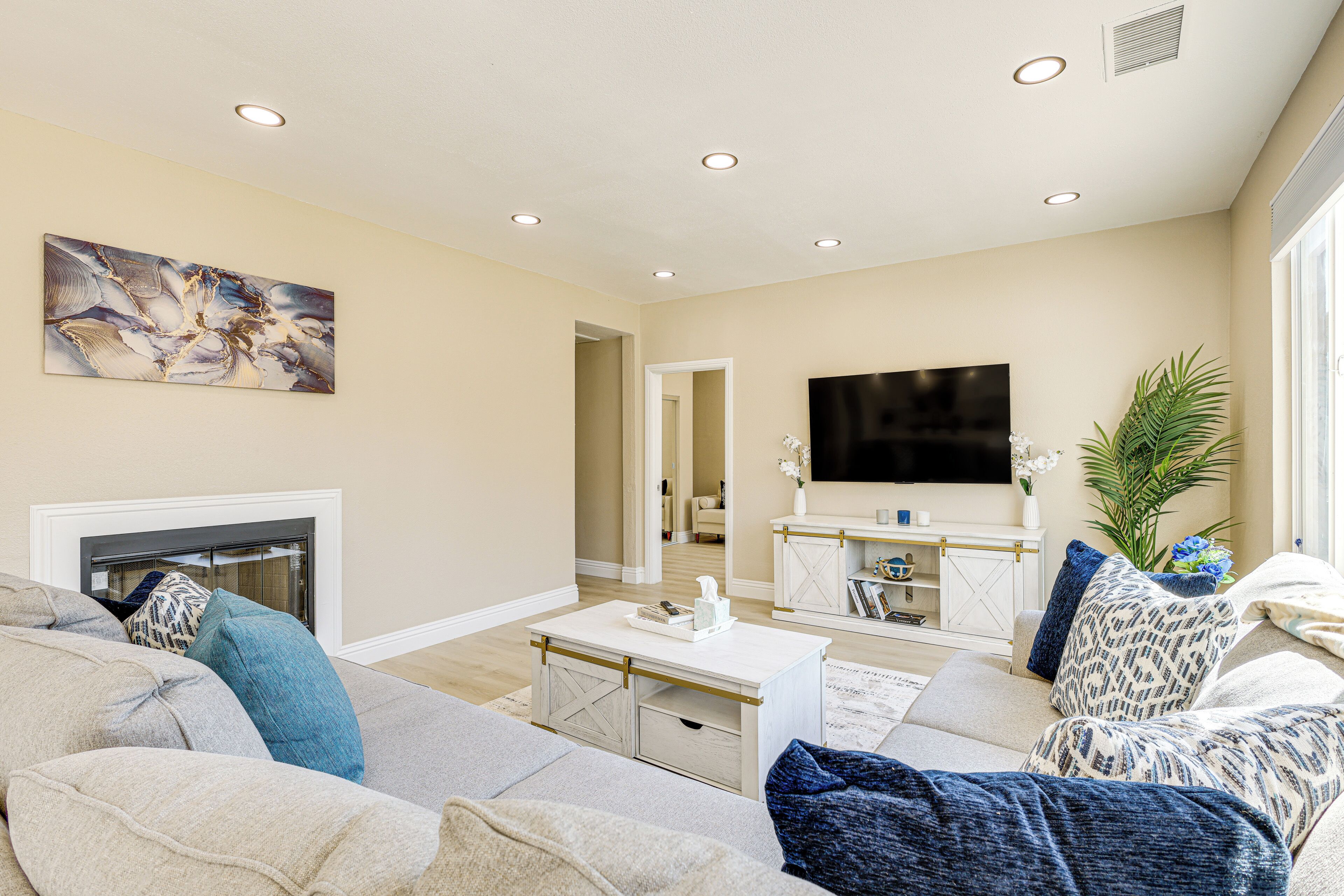 A living room with a fireplace, a flat-screen TV, and a large painting on the wall.