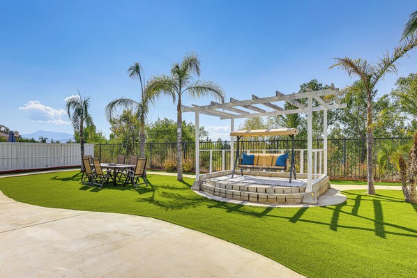 Un espace patio agrémenté d’une pergola, de meubles de jardin et d ’une pelouse bien entretenue.