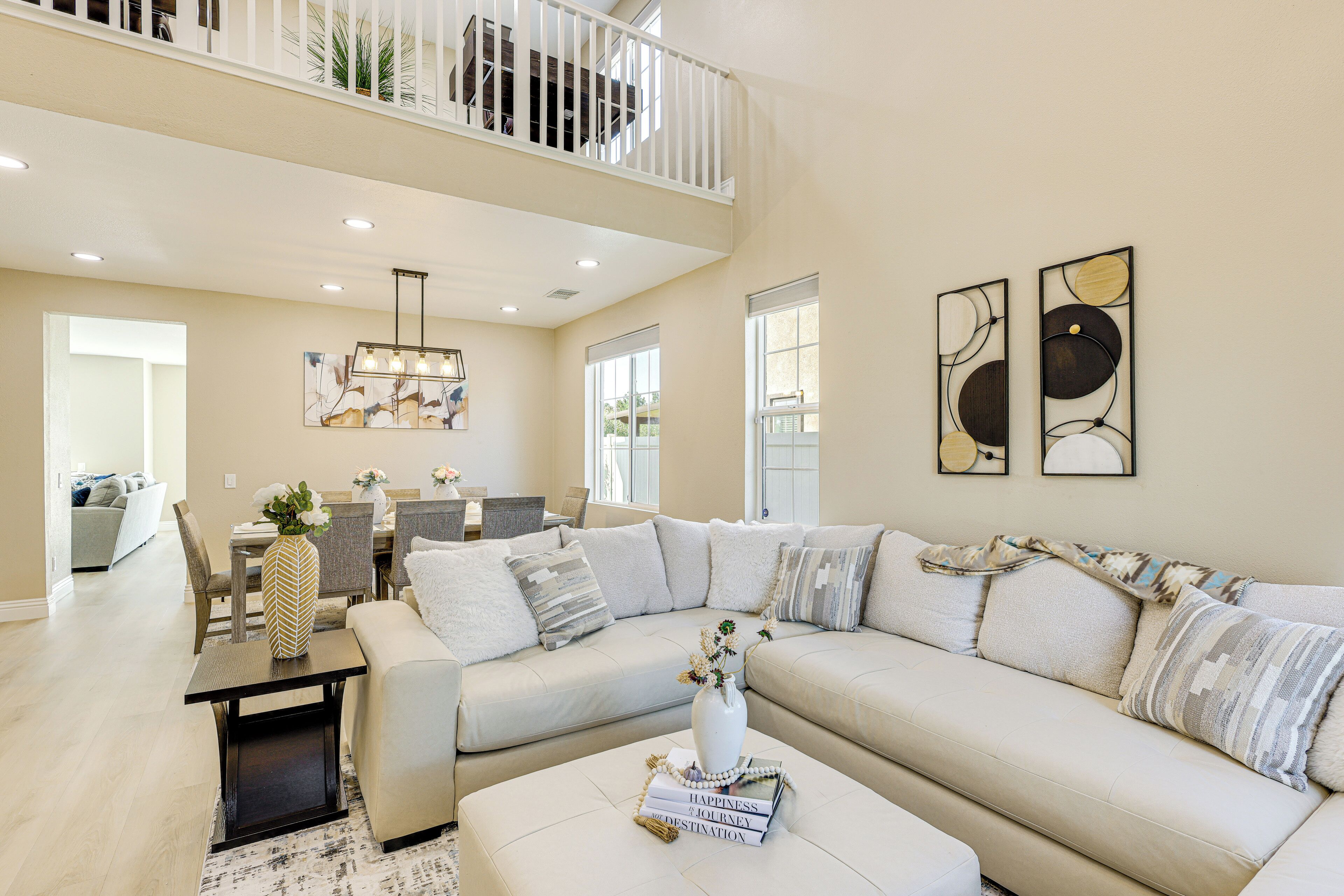 A spacious living room with a high ceiling, a dining area, and a balcony.