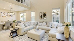 A spacious living area with a large L-shaped sectional sofa, a dining table with chairs, and a staircase leading to an upper level. - Mtn-view Gem w/ Private Yard: Luxe Beaumont Home (Beaumont)