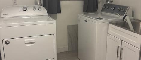 Une buanderie équipée d’un lave-linge à chargement frontal, d’un sèche-linge et d’une cuisinière.