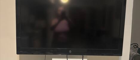 Televisor de pantalla plana montado en una pared blanca, con cables a la vista.