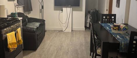 A compact living space with a kitchen, dining area, and a flat-screen TV mounted on the wall.