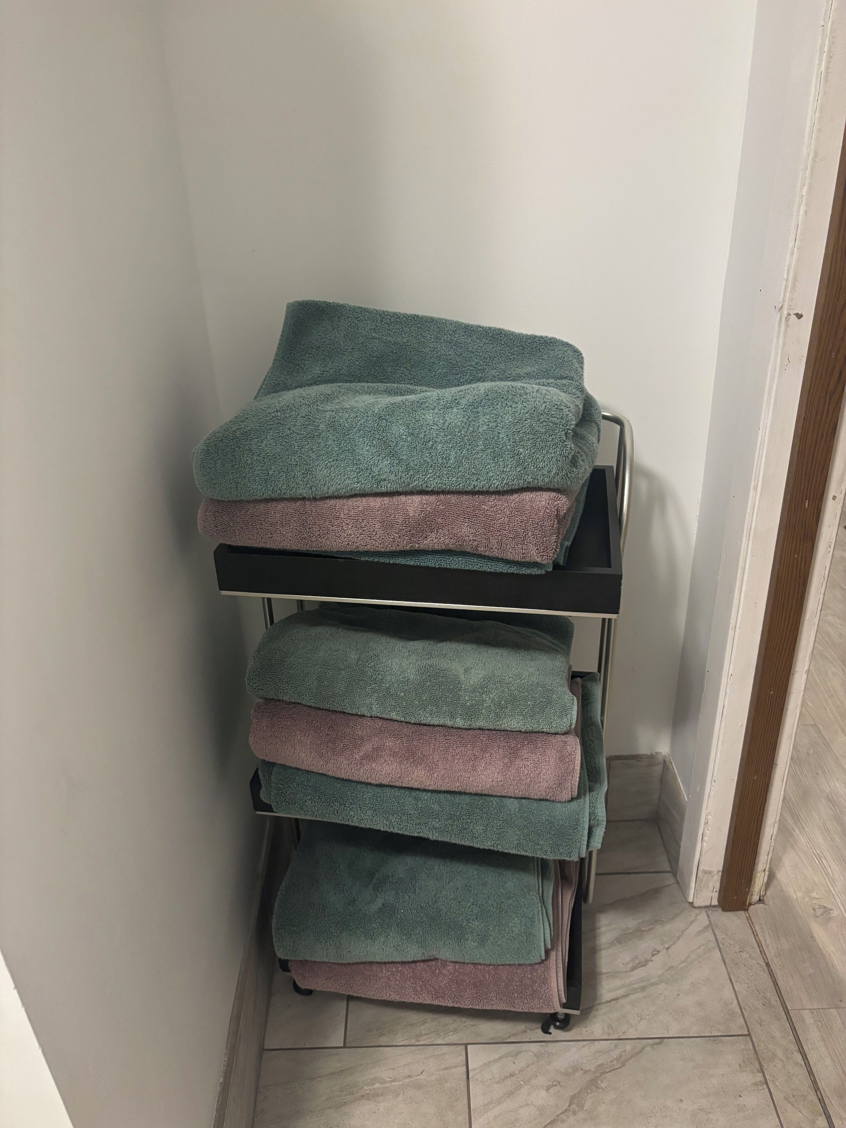 A stack of folded towels on a metal cart in a corner.