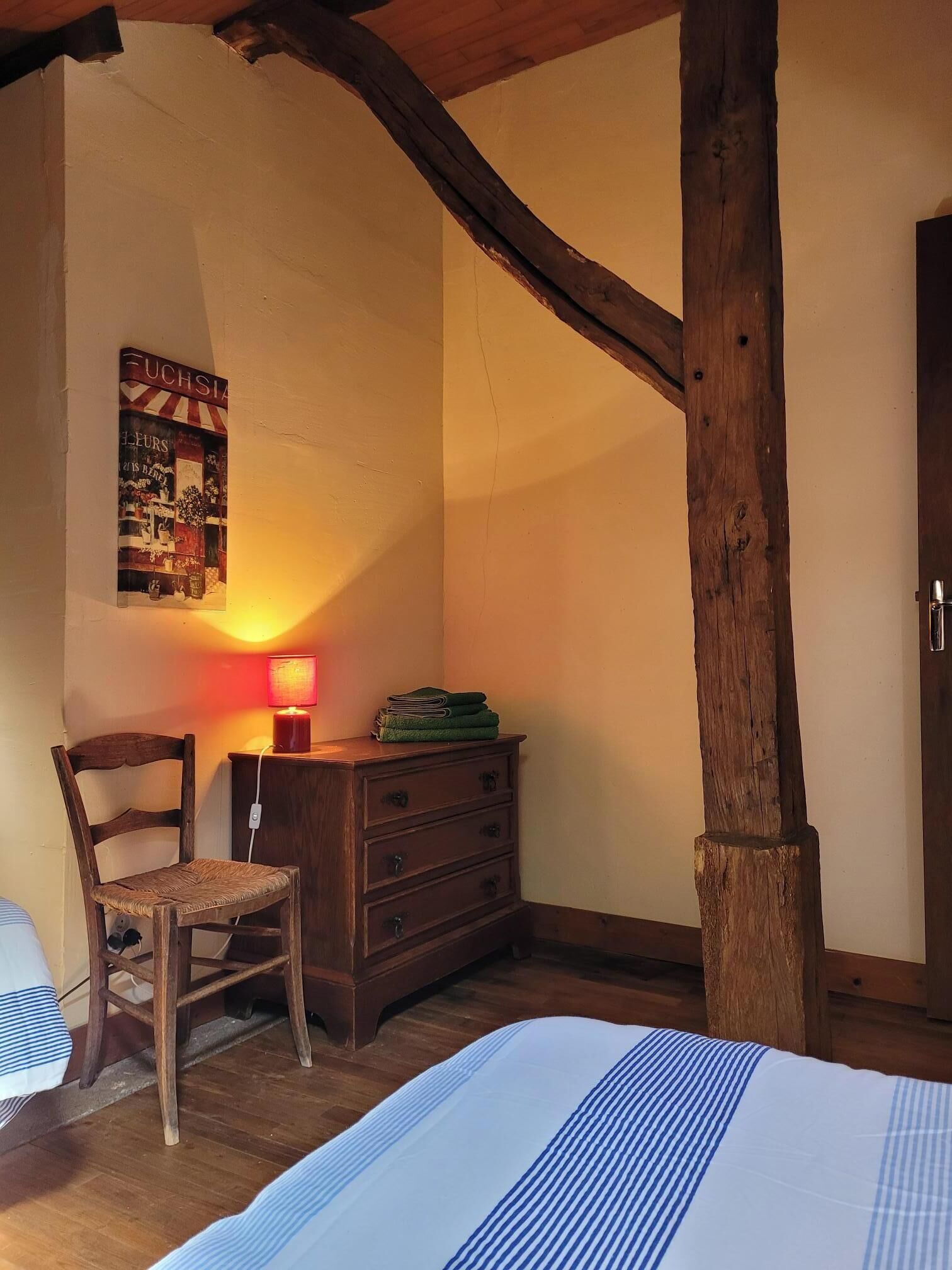 A cozy room with a wooden chair, a dresser, and a bed.