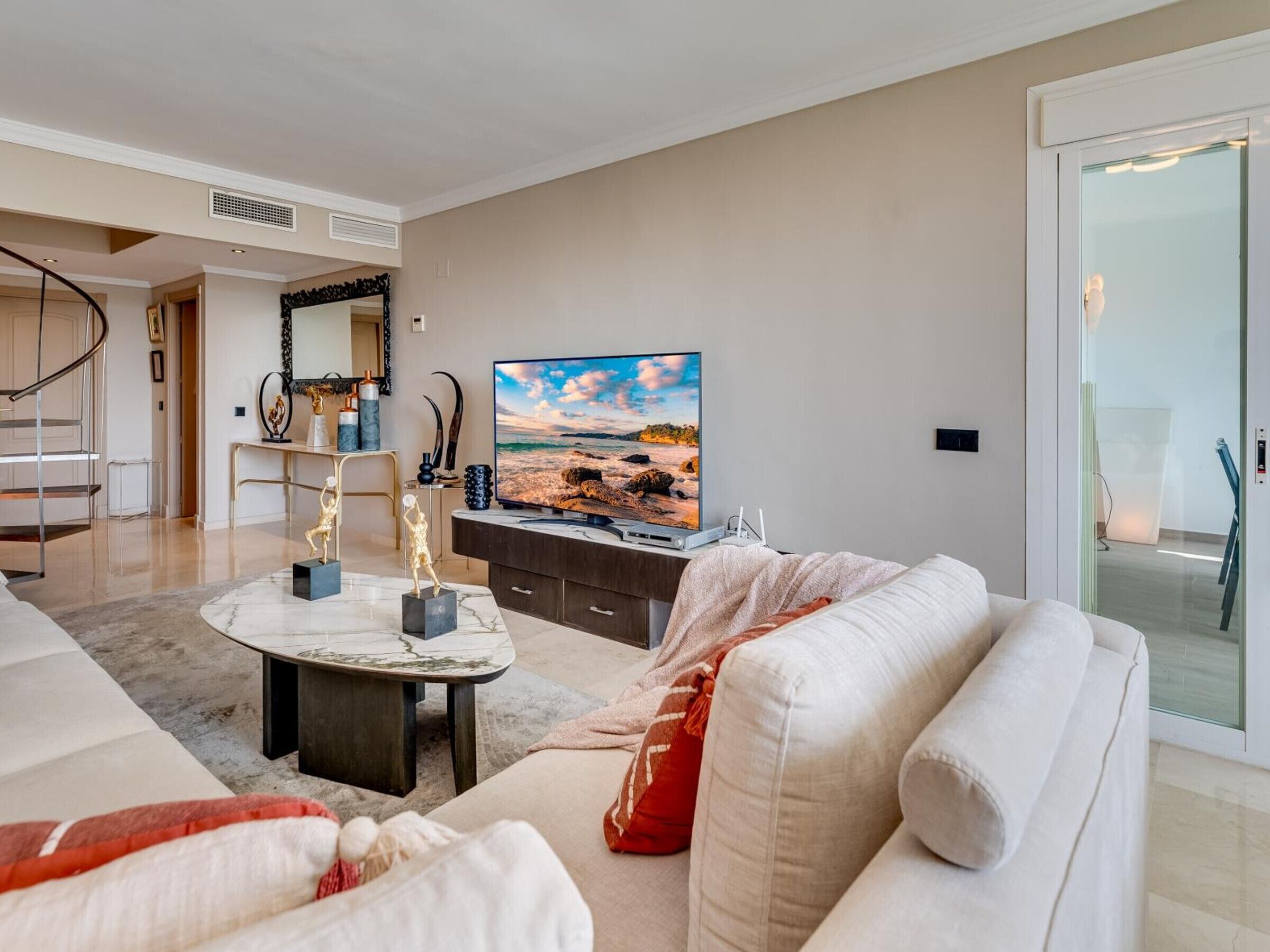 A modern living room with a sofa, a coffee table, and a flat-screen TV.