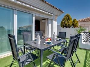 A patio with a table set for four, surrounded by chairs, and a glass door leading to an interior space.