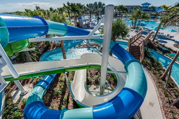 A water park with multiple slides and pools, surrounded by palm trees and lounge areas.