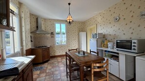 Une cuisine compacte comprenant une table à manger, des chaises en bois, une cuisinière, un four à micro-ondes et un réfrigérateur.