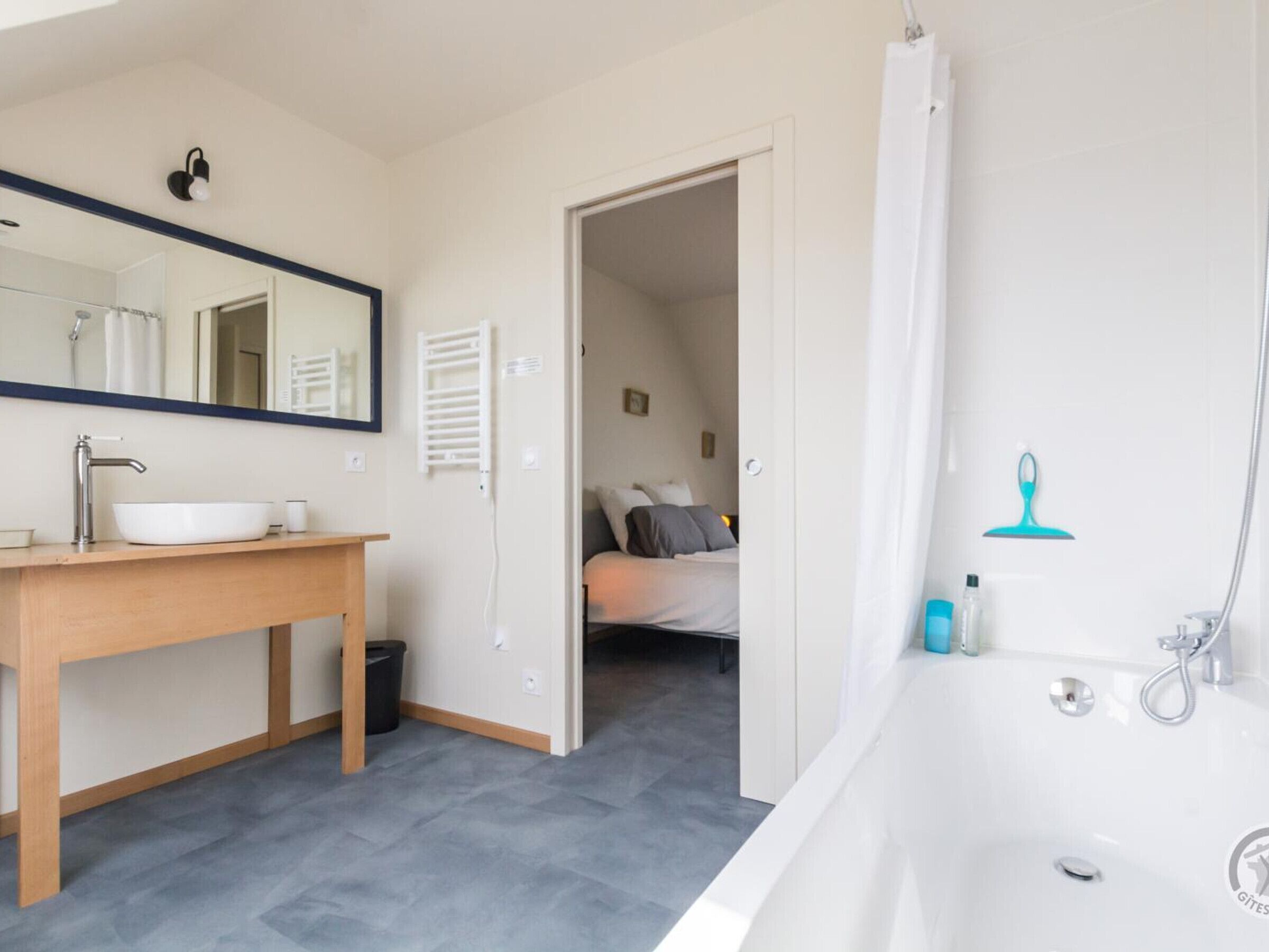 A modern bathroom with a large bathtub, a sink with a mirror, and a shower area.