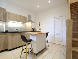 Cozinha moderna com armários de madeira, bancada preta, ilha central com banquetas e porta branca.
