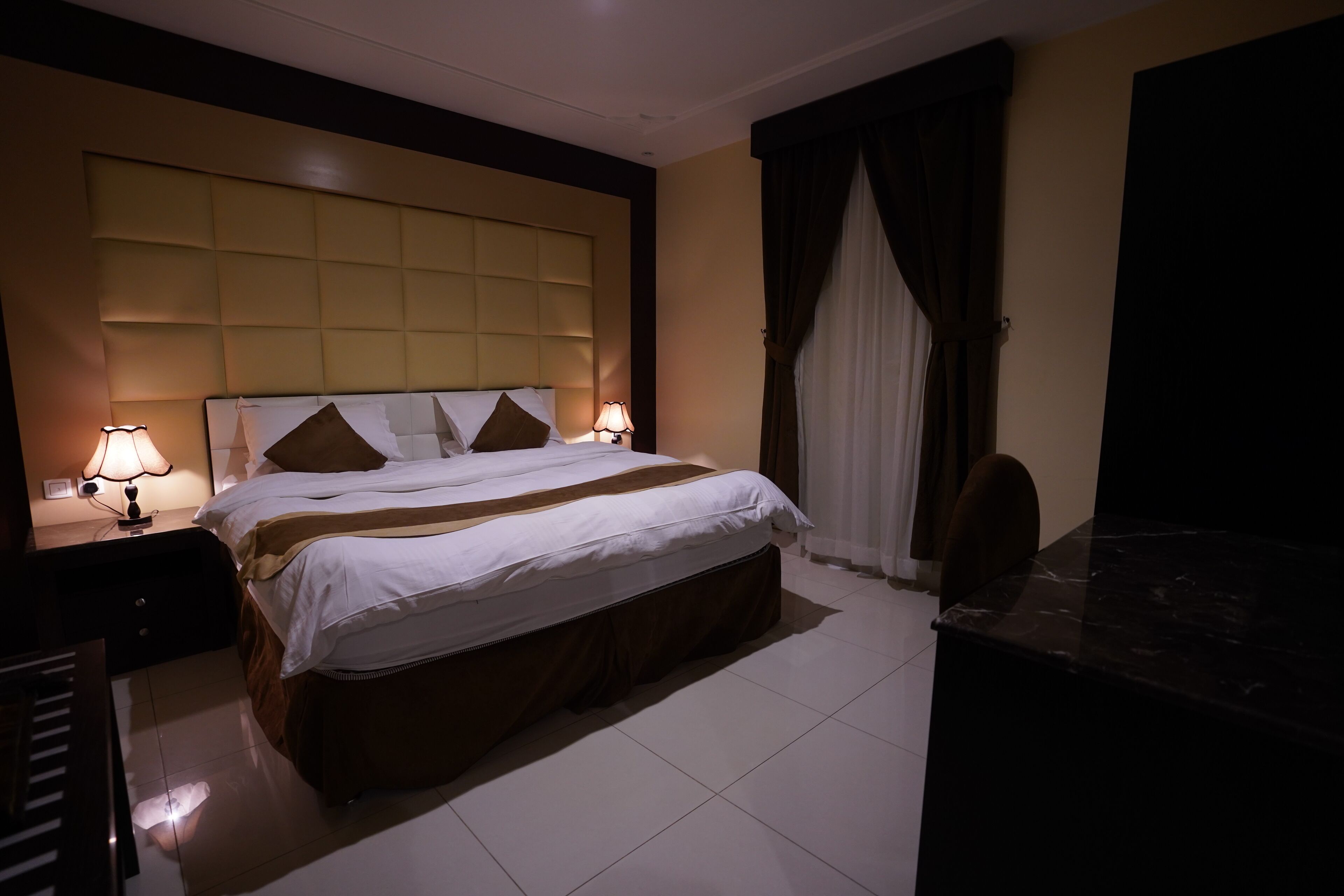 Een hotelkamer met een groot bed, twee nachtkastjes met lampen, een bureau en een stoel.