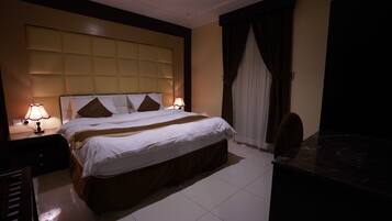 Een hotelkamer met een groot bed, twee nachtkastjes met lampen, een bureau en een stoel.