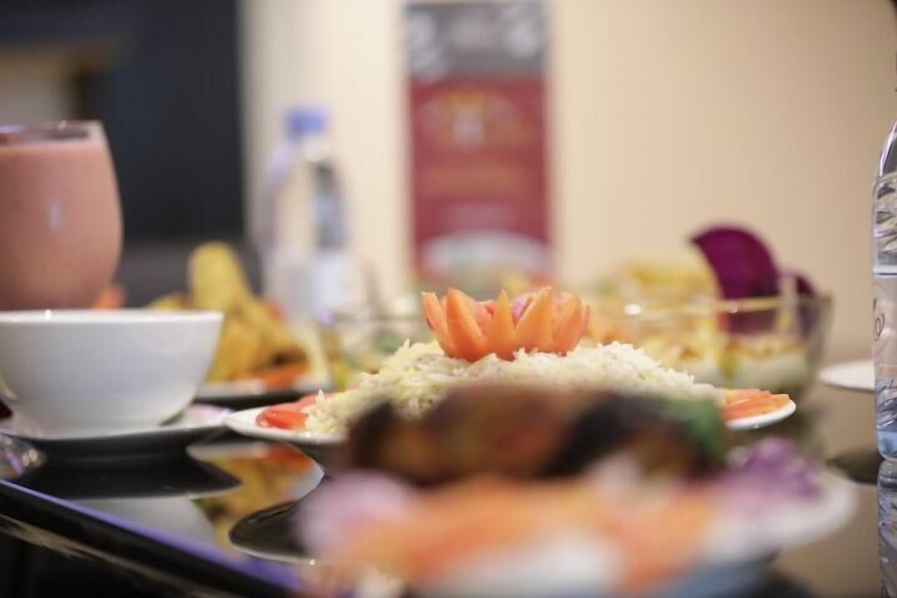 A dining table with various dishes, including rice and vegetables, and a glass of beverage.