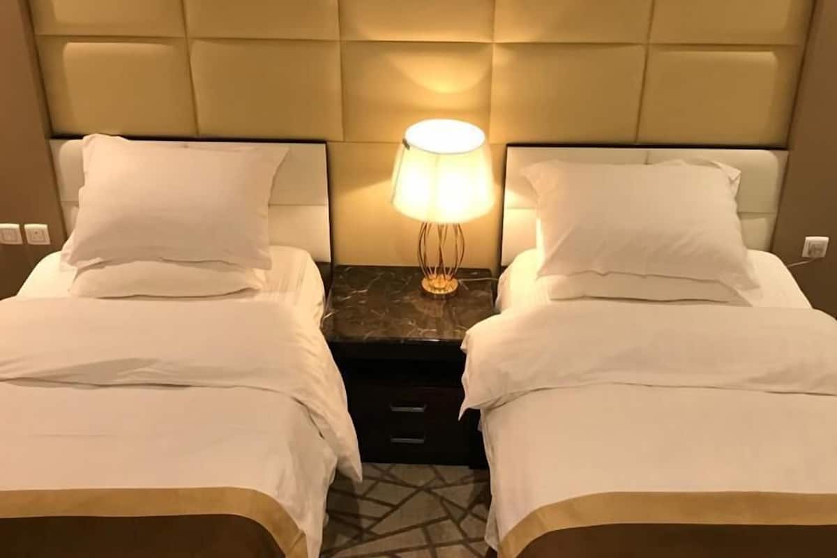 Une chambre d’hôtel avec deux lits, une table de chevet avec une lampe et un sol à motifs.