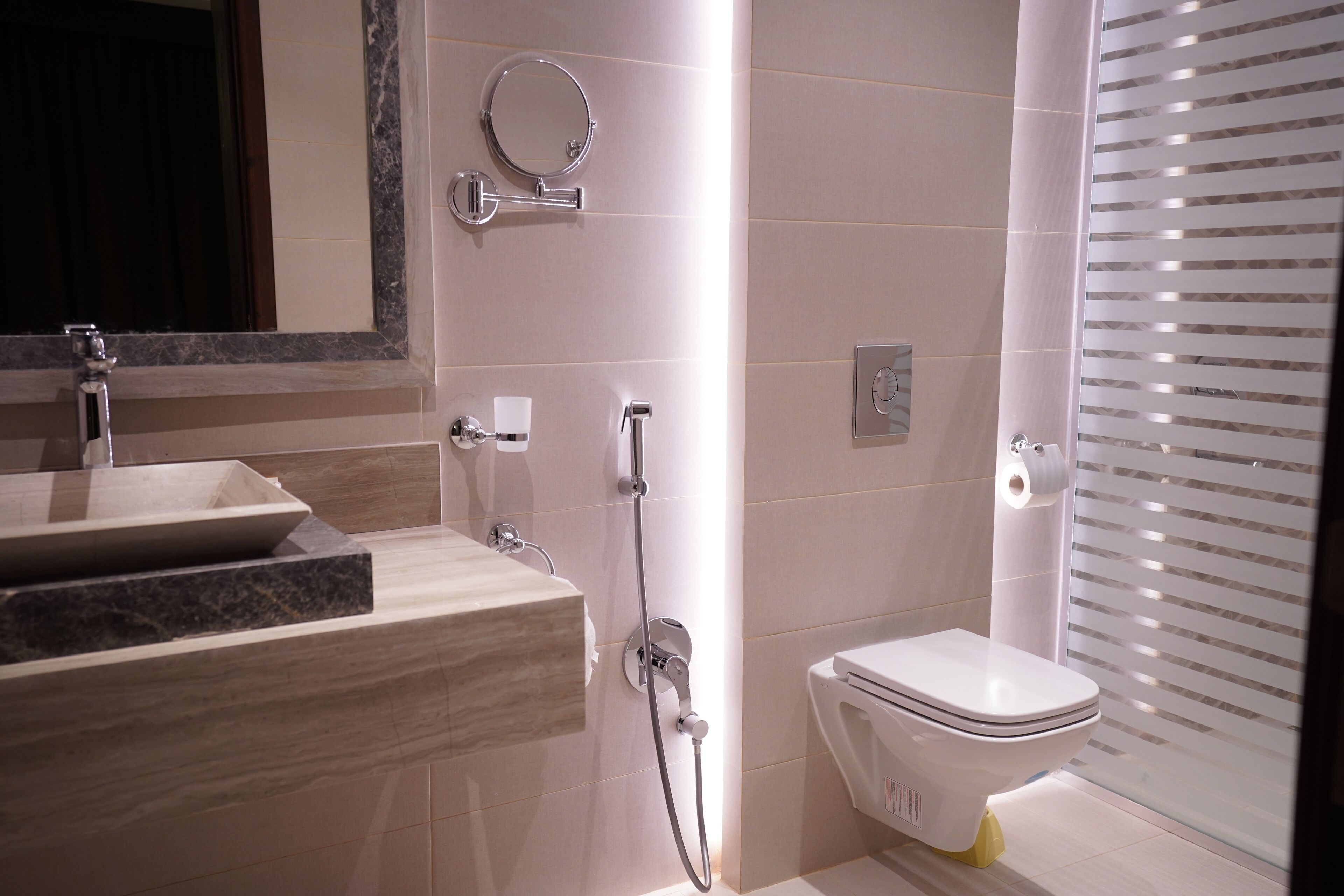 A modern bathroom with a sink, mirror, toilet, and shower.