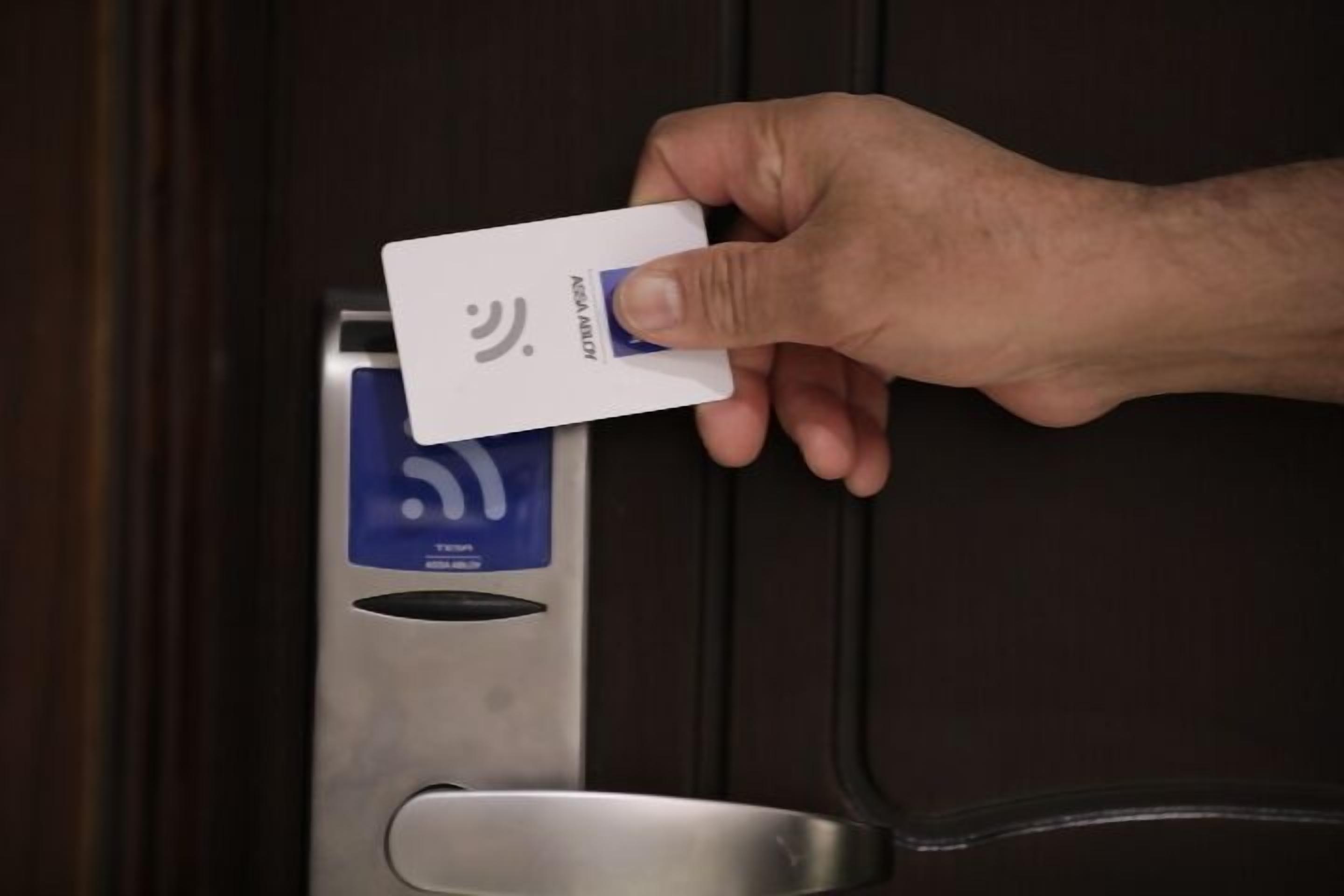 Une main tenant une carte près d’un lecteur de cartes.