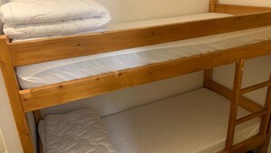 Un lit superposé à deux niveaux, chaque niveau étant équipé d’un matelas et d’un oreiller blancs.