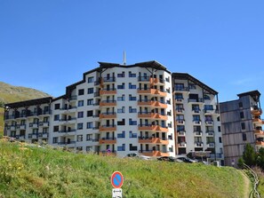 A multi-story hotel with balconies, a parking area, and a no-parking sign.
